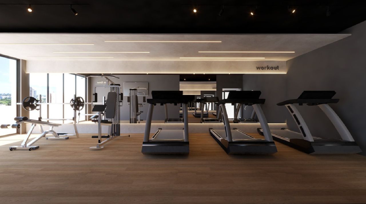 Academia com esteiras, equipamentos de musculação, piso amadeirado e iluminação linear no teto